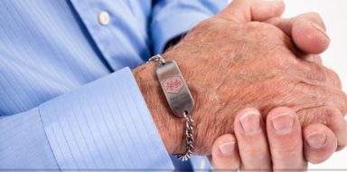 A medical alert bracelet on a senior man's wrist.